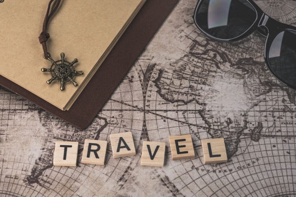 Close-up of travel items including map, helm pendant, notebook, and sunglasses.